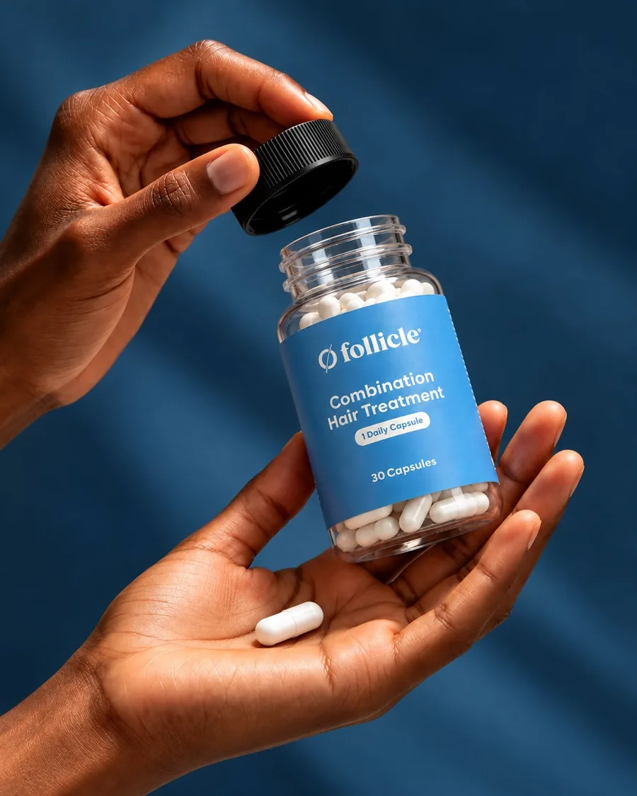 Two hands holding a Follicle capsule bottle against a navy background
